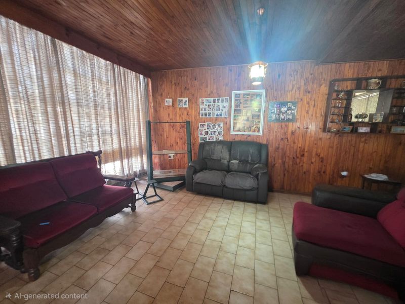 Living room featuring extensive wood panelled walls and ceiling with tiled flooring and built-in shelving.