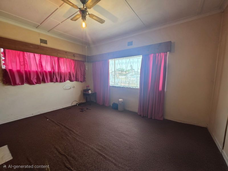 A vacant living room featuring a ceiling fan, security bars on windows, and dated wall-to-wall carpeting in need of refurbishment.