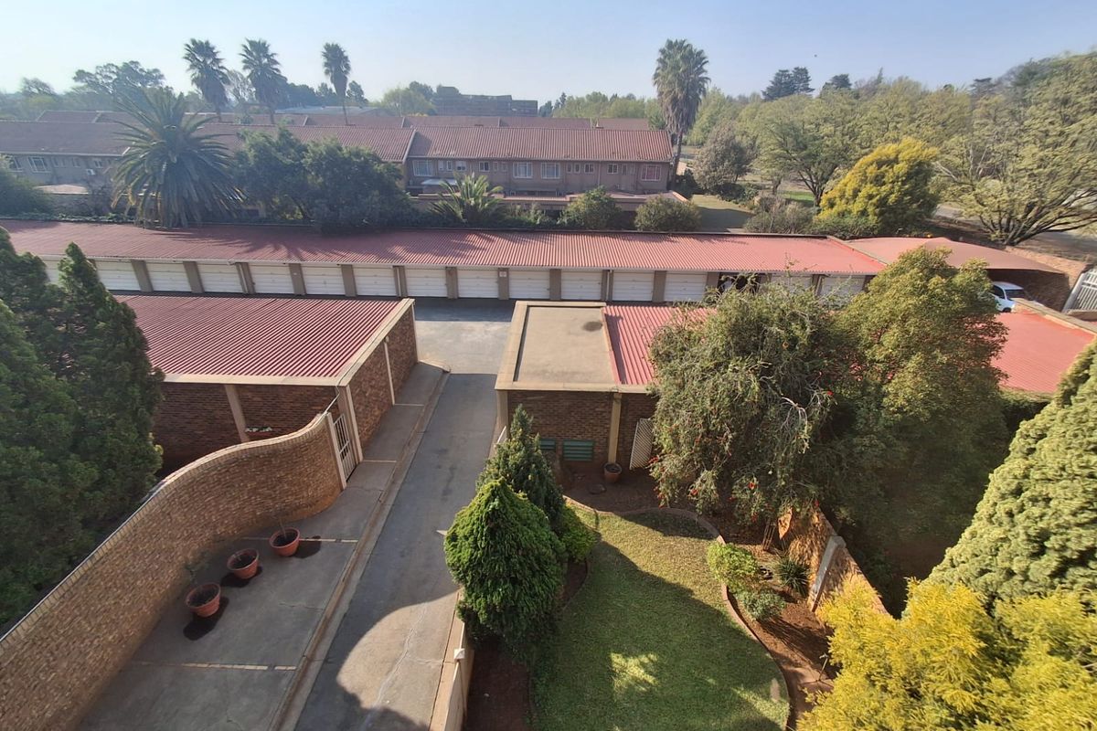 An elevated aerial view of the residential complex, showcasing the garage block, paved driveway, and surrounding landscaped garden areas.