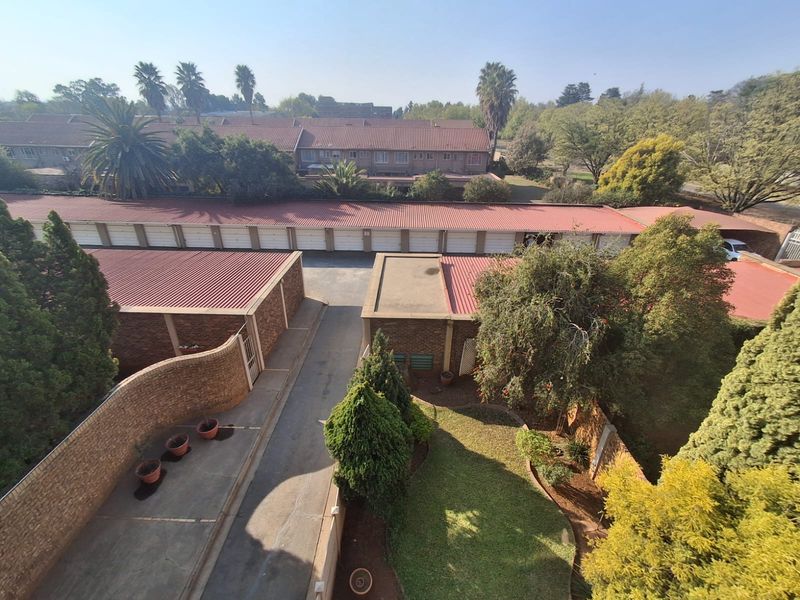 An elevated aerial view of the residential complex, showcasing the garage block, paved driveway, and surrounding landscaped garden areas.