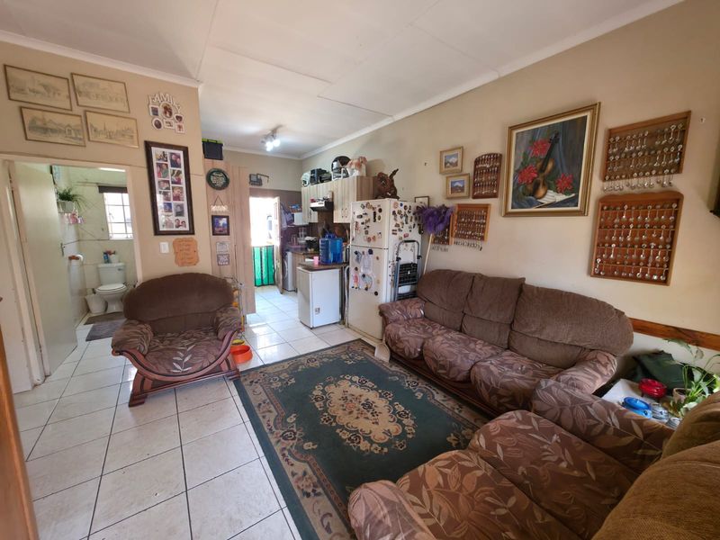 Open plan living area featuring ceramic floor tiles and an adjoining kitchen space with built-in cabinetry.