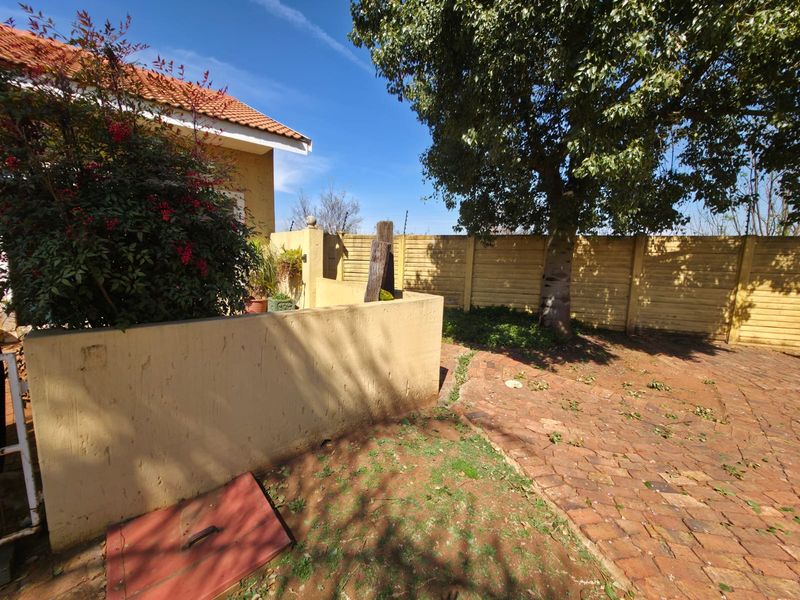 A rear garden area featuring brick paving, a precast concrete boundary wall, and a mature tree, providing a private outdoor space.
