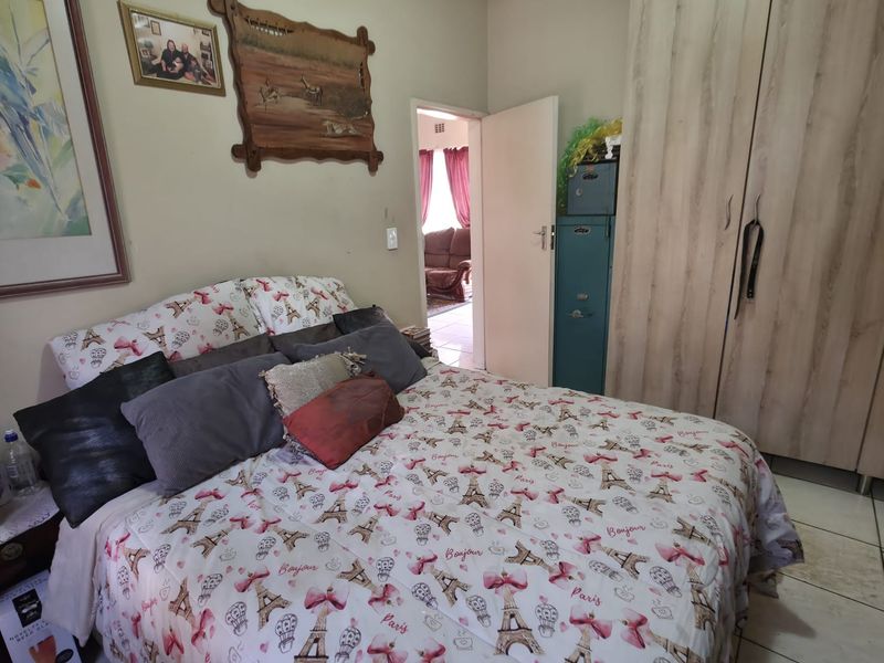 A bedroom featuring tiled flooring and a built-in wardrobe, offering a functional space with direct access to an adjacent room.