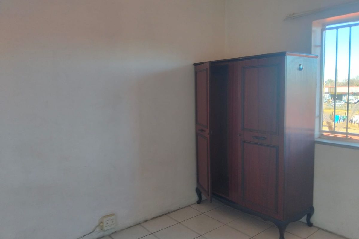A bedroom featuring tiled flooring and a window with security bars, requiring minor cosmetic updates to the wall finishes.