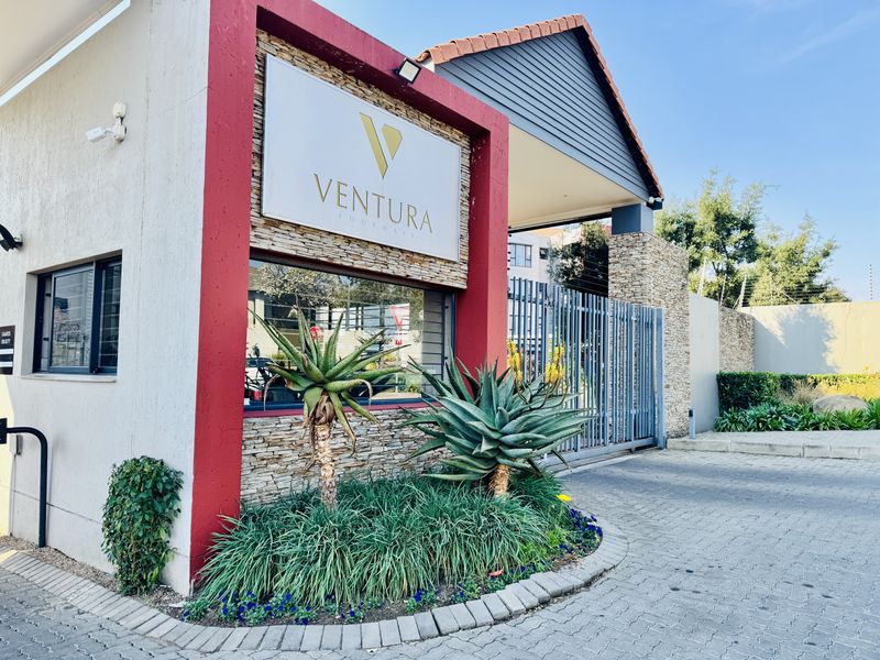 The secure entrance gate and guardhouse of the Ventura Fourways complex, featuring stone cladding, paved driveway, and modern signage.