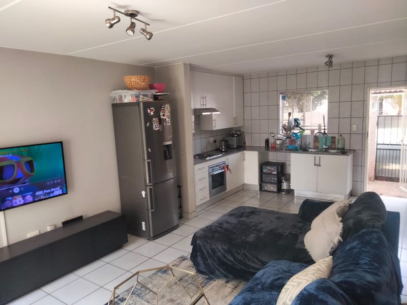 Open-plan living area featuring a functional kitchen with built-in cabinetry, stainless steel oven, gas hob, and tiled flooring throughout.