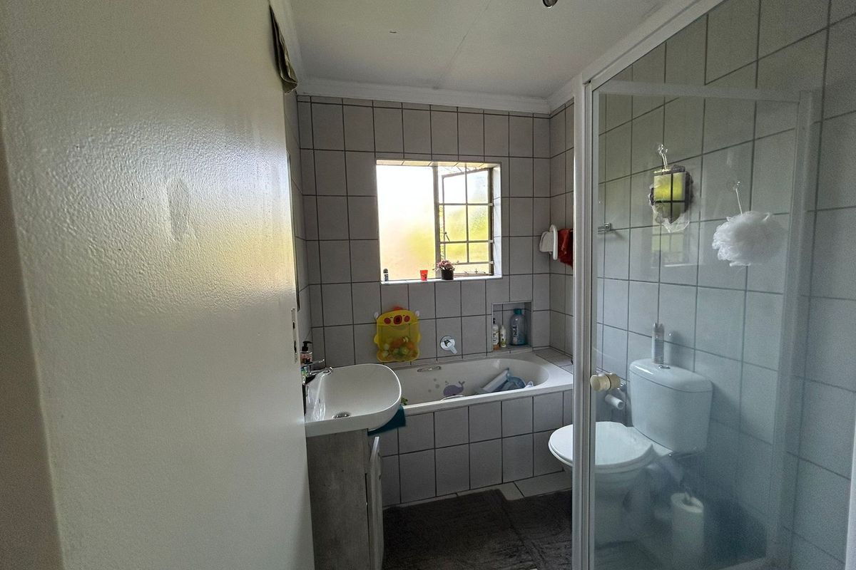 A functional bathroom featuring a built-in bathtub, separate shower enclosure, toilet, and vanity basin with tiled finishes and a recessed wall niche.