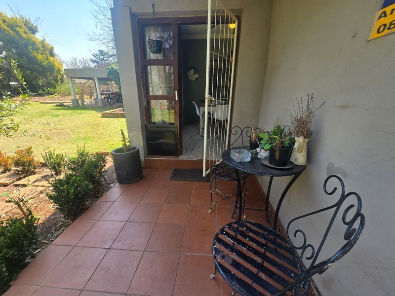 A covered patio area featuring tiled flooring and a security gate, providing direct access to the garden.