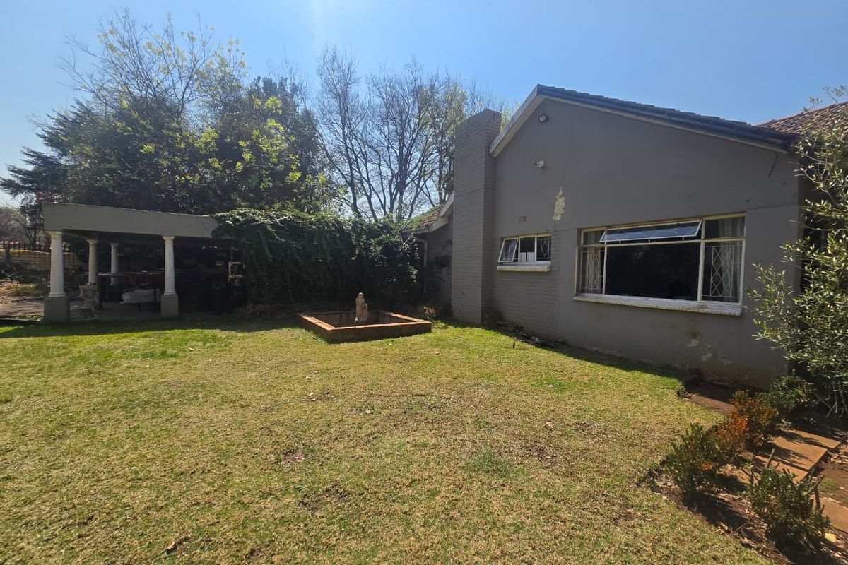 Rear view of the property featuring a lawn, a masonry fountain, and a covered patio area attached to the main building structure.
