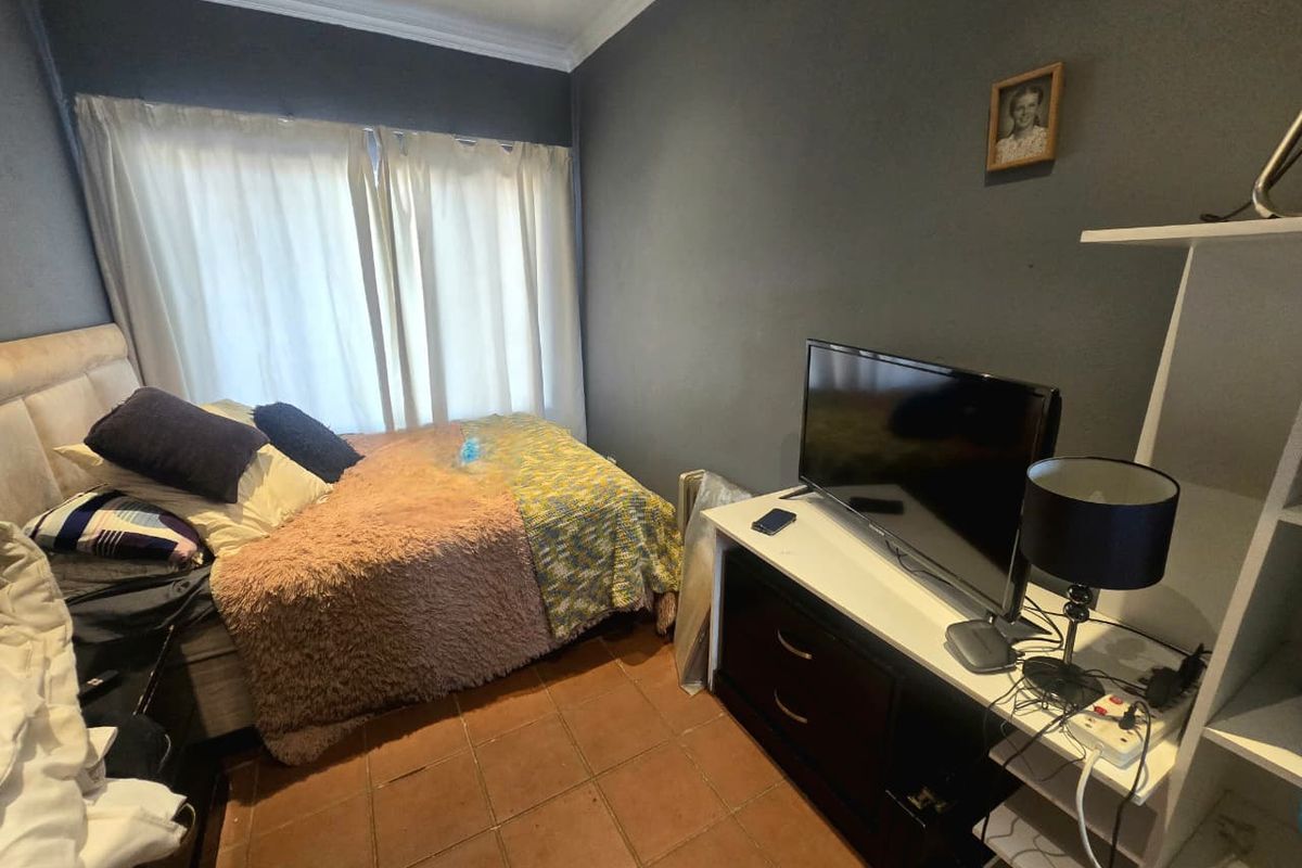 A compact bedroom featuring tiled flooring and crown molding, providing a functional space with neutral wall tones.