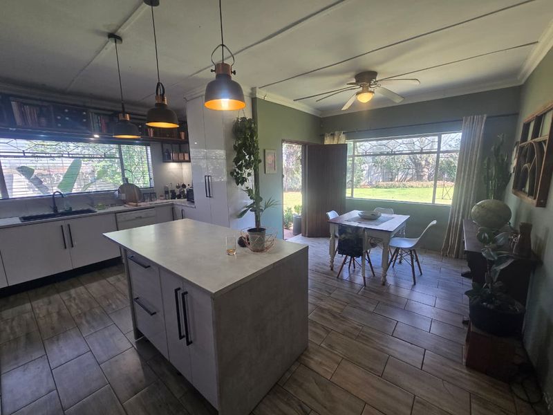 Spacious open-plan kitchen and dining area featuring a central island, modern cabinetry, tiled flooring, and direct access to the garden.