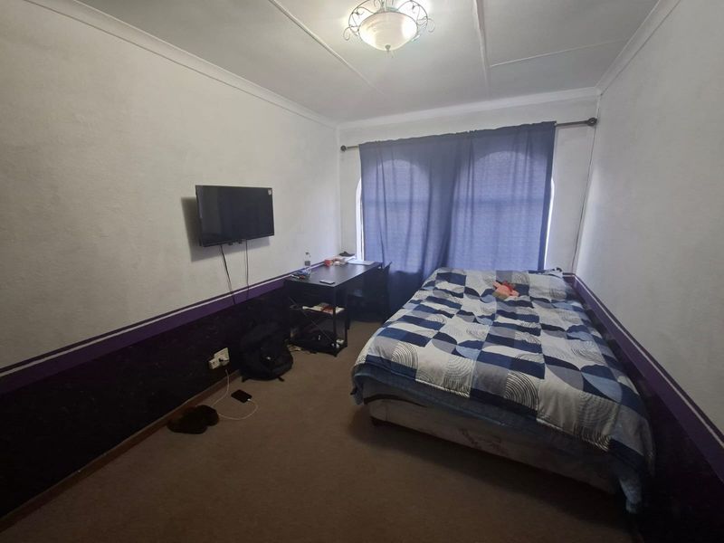 A standard bedroom featuring carpeted flooring, ceiling coving, and wall-mounted electrical points, requiring cosmetic updates to improve its overall appeal.