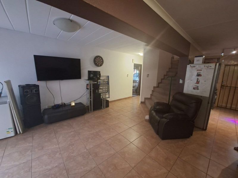 Open plan living area featuring ceramic floor tiles and a staircase leading to the upper level.