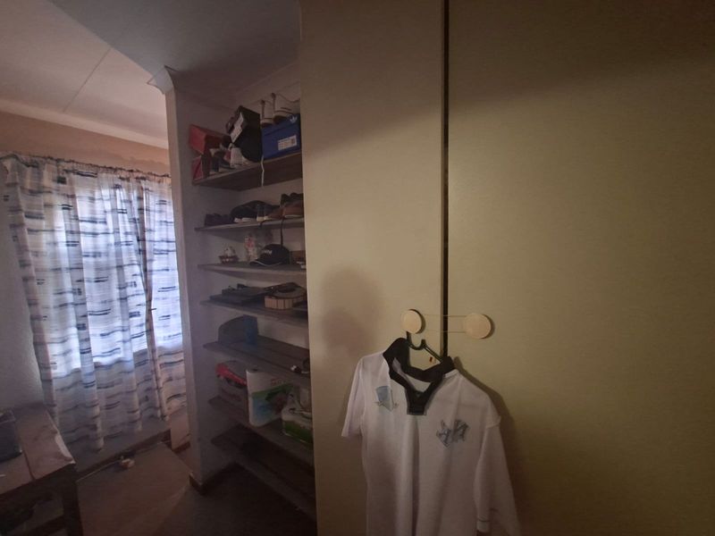 A bedroom featuring a built-in wardrobe and open shelving storage, with a window providing natural light.