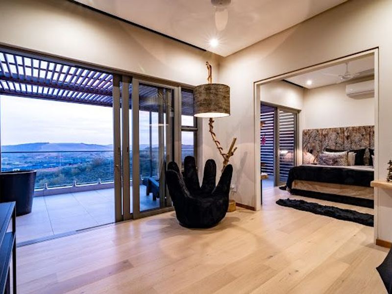 Modern living area featuring expansive sliding glass doors opening to a balcony with scenic views, complemented by light hardwood flooring and integrated lighting.