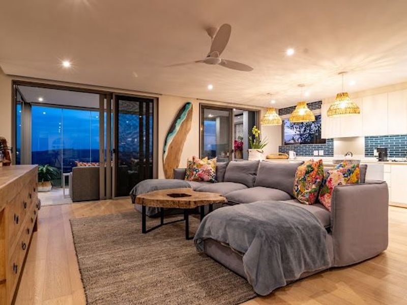 Modern open-plan living area featuring hardwood floors, recessed lighting, a ceiling fan, and seamless access to an outdoor patio through large sliding glass doors.