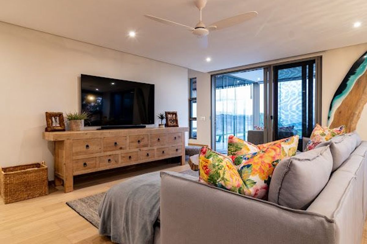 Modern living room featuring hardwood flooring, recessed lighting, a ceiling fan, and large sliding glass doors providing access to the outdoor area.