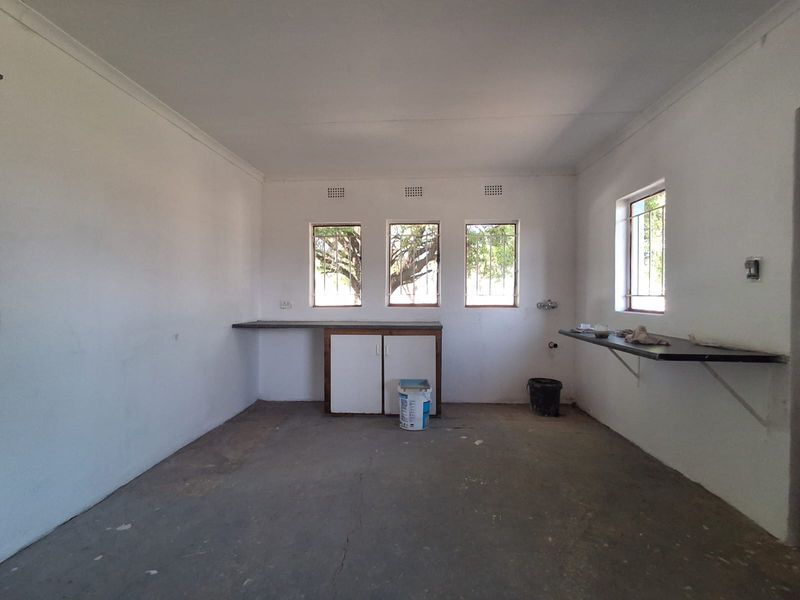 A functional scullery or utility space featuring built-in cabinetry, countertop workspace, and plumbing connections, ready for renovation or custom finishing.