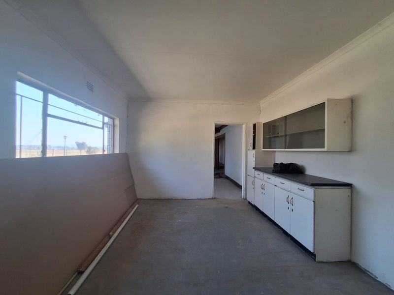 A functional scullery or utility space featuring built-in cabinetry, wall-mounted storage cupboards, and a large window with views of the surrounding farm landscape.
