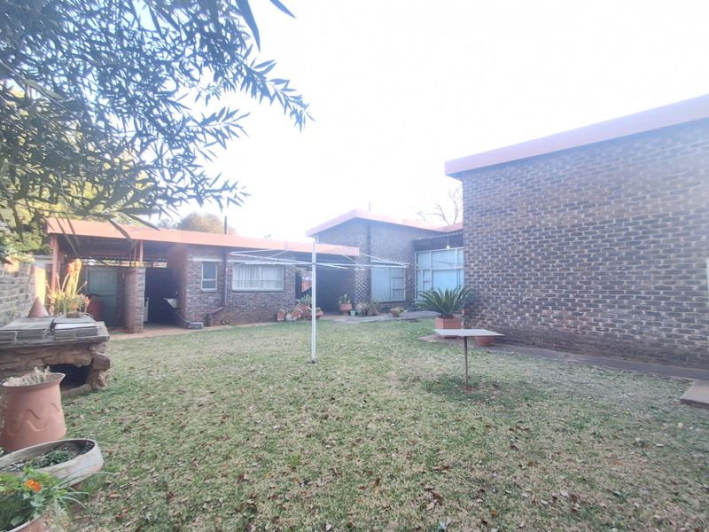 A rear view of the property featuring face brick walls, a covered patio area, and a private garden space.