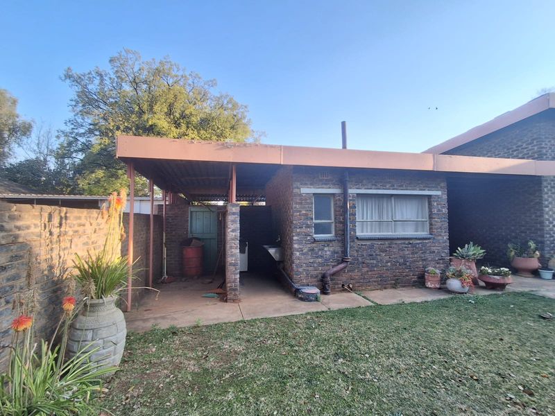 Rear exterior view of the house featuring a covered patio area with a utility sink, brick facade, and access to the garden.