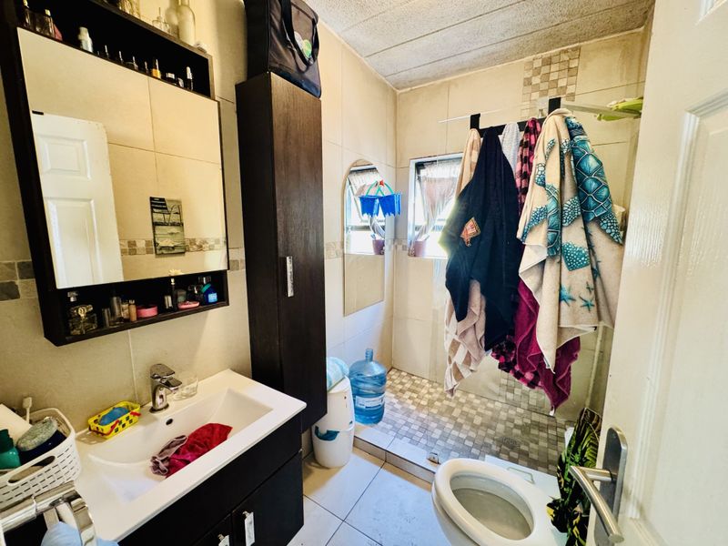 A functional bathroom featuring a vanity unit, toilet, and a walk-in shower area with tiled finishes throughout.