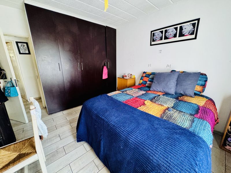 A bedroom featuring dark built-in cupboards and tiled flooring, offering a functional space with potential for cosmetic updates.
