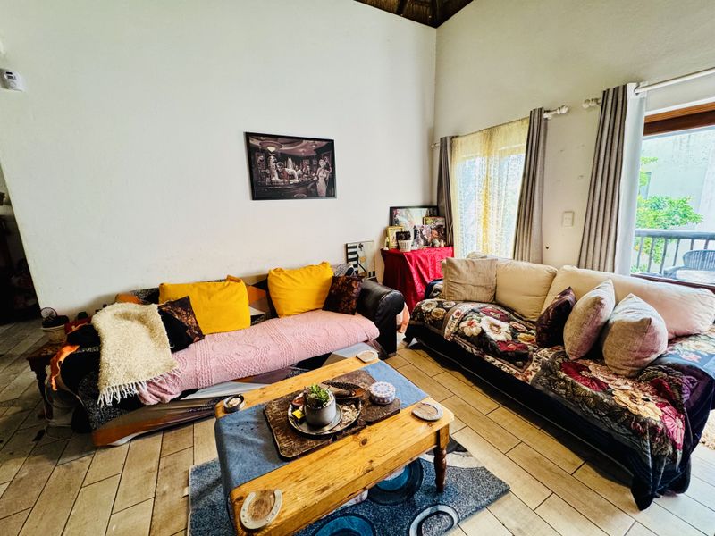A living room featuring tiled flooring, a high vaulted ceiling, and a sliding glass door providing access to an outdoor area.