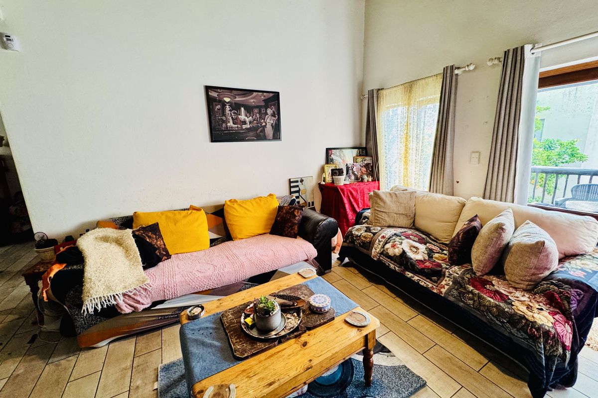 A living room featuring tiled flooring, a high vaulted ceiling, and a sliding glass door providing access to an outdoor area.
