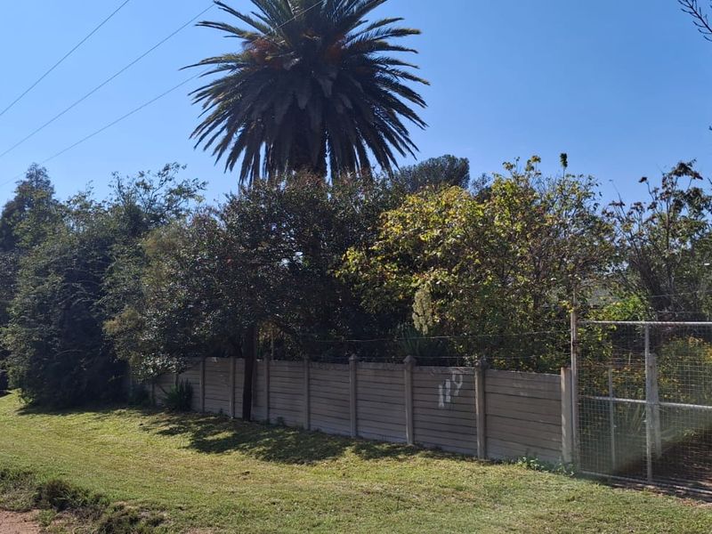 Street view of the farm property featuring a precast concrete boundary wall, wire mesh fencing, and roof-mounted solar panels and geyser.