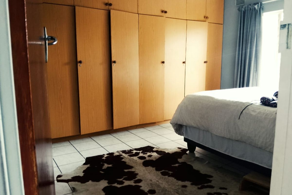 A bedroom featuring extensive floor-to-ceiling built-in wooden cupboards and tiled flooring, offering ample storage space.