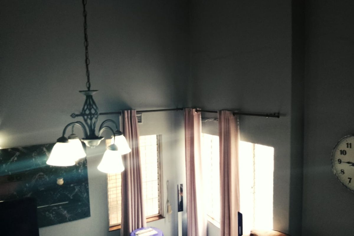 A living room area featuring high vaulted ceilings, a decorative chandelier, and large windows with curtain rods.