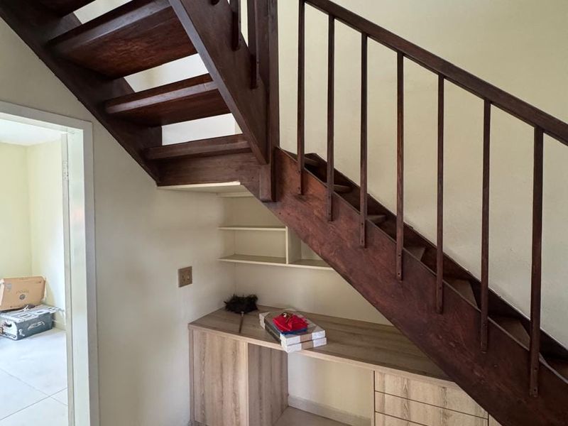 A functional utility space featuring a wooden staircase with integrated built-in desk and cabinetry, providing efficient storage and workspace under the stairs.
