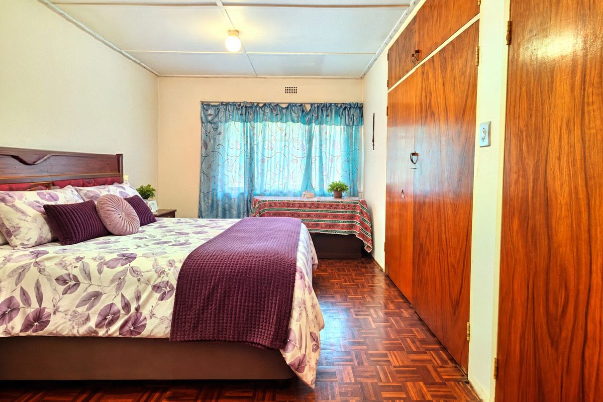 A bedroom featuring classic parquet flooring, built-in wooden cupboards, and a standard ceiling, offering a functional space with potential for modern updates.