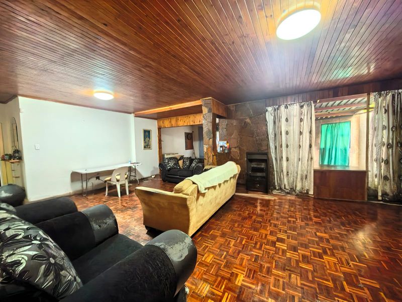 Spacious living room featuring traditional parquet flooring, a timber-clad ceiling, and a stone feature wall with a built-in fireplace.