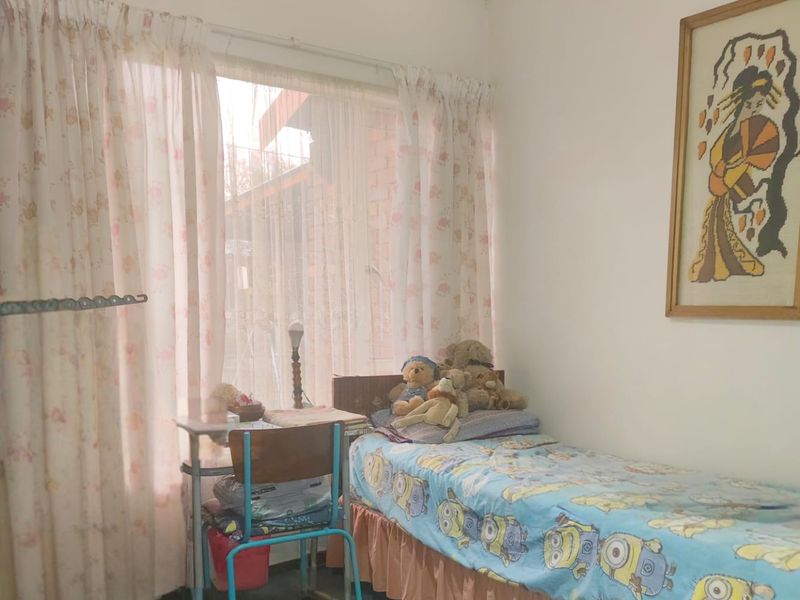 A functional bedroom featuring a large window with curtain tracks and a central ceiling light fixture.