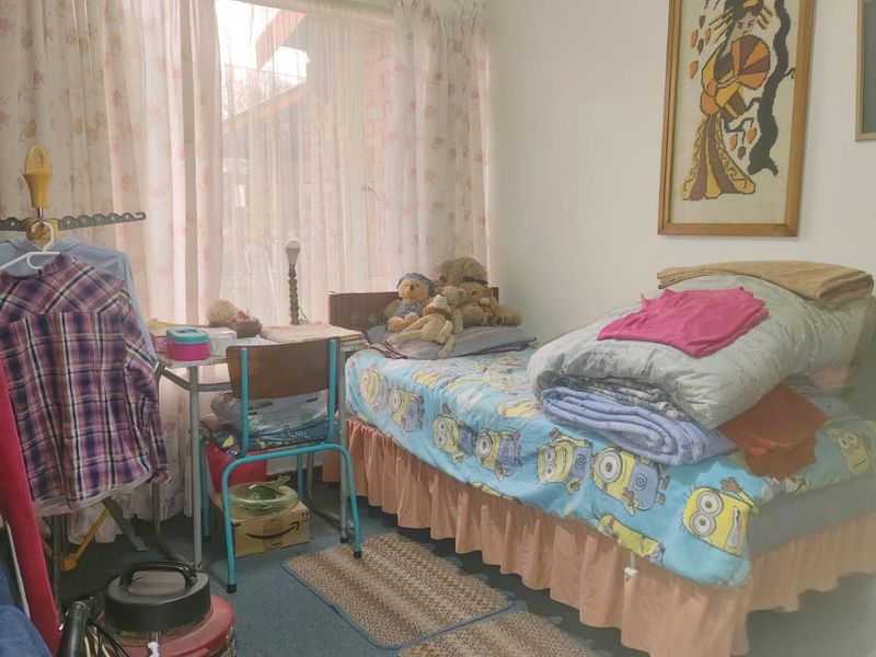 A functional bedroom featuring carpeted flooring and a large window, providing a comfortable space for rest.
