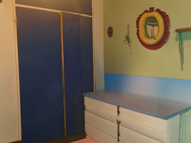 A bedroom featuring a built-in wardrobe and integrated storage cabinetry, offering potential for modernization and aesthetic updates.
