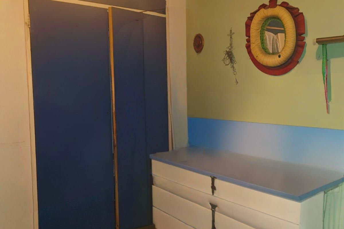 A bedroom featuring a built-in wardrobe and integrated storage cabinetry, offering potential for modernization and aesthetic updates.