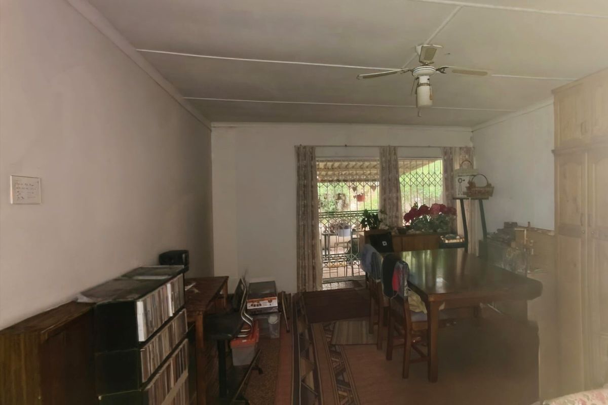A living area featuring a ceiling fan, built-in cabinetry, and a sliding door leading to an outdoor space, requiring cosmetic updates to modernize the interior.