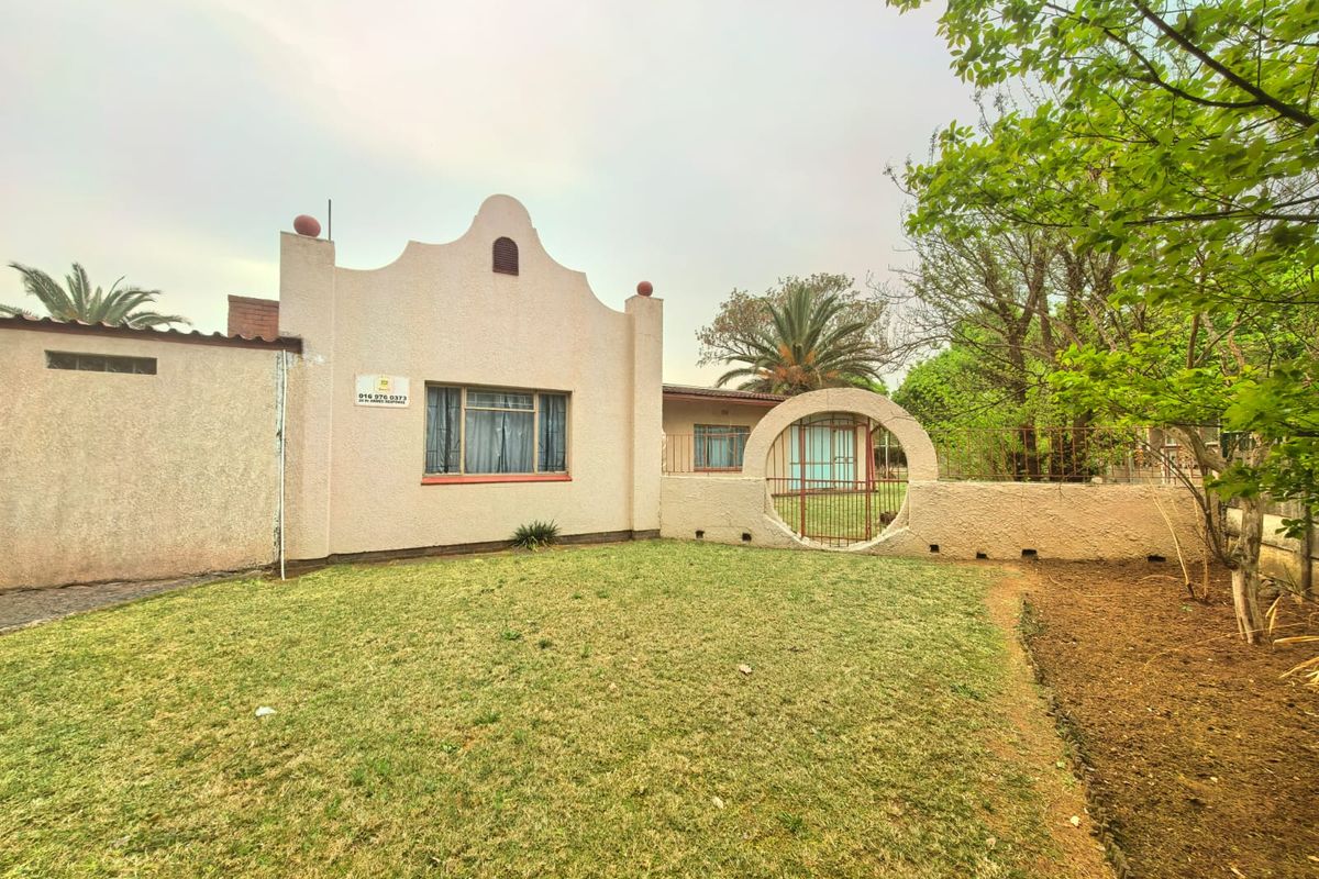 Rear exterior view of the property featuring a stucco facade, a unique circular gate, and a private garden area.
