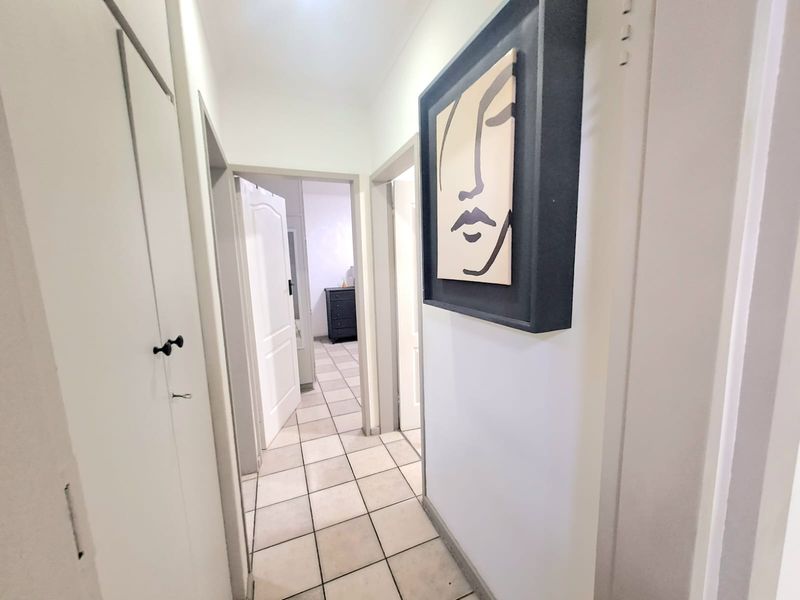 A tiled hallway providing access to adjacent rooms, featuring a built-in storage cupboard.