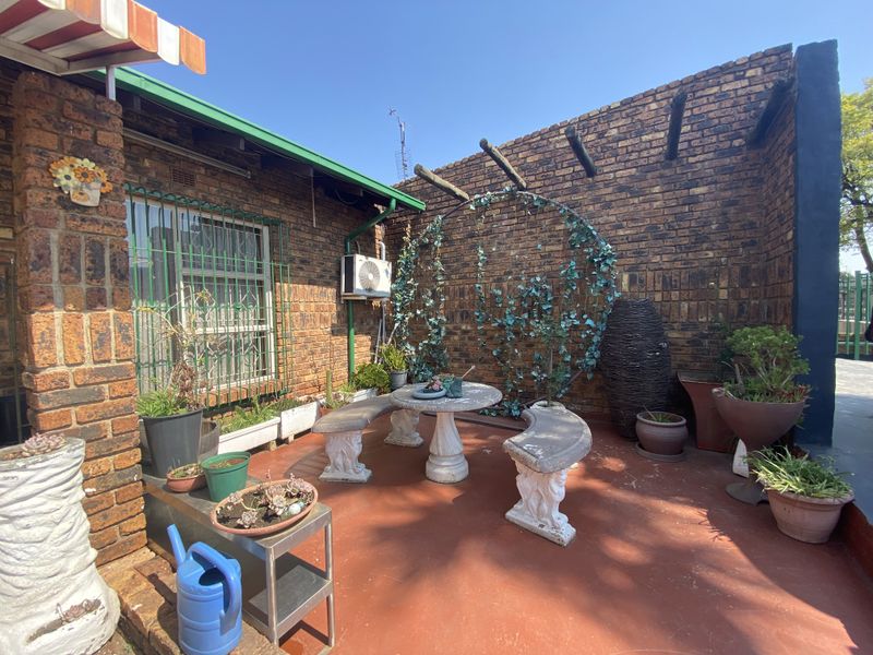 A private outdoor patio area featuring exposed brick walls, a pergola structure, and an installed air conditioning unit.