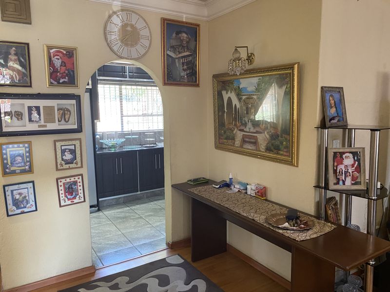 A living area featuring an arched doorway leading into a kitchen with dark cabinetry and tiled floors.