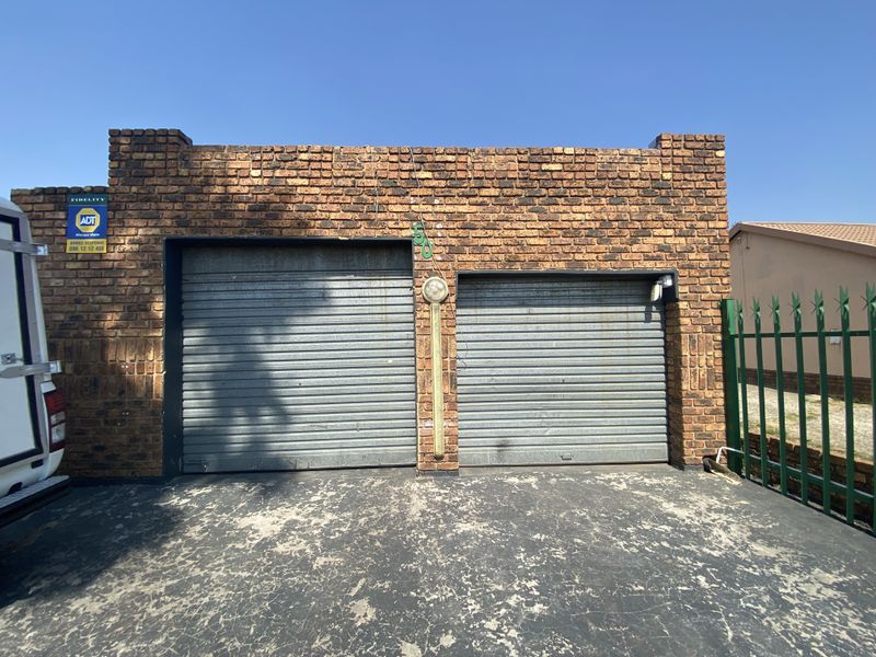 A double garage featuring a face brick exterior with two roller doors and an integrated security alarm system.