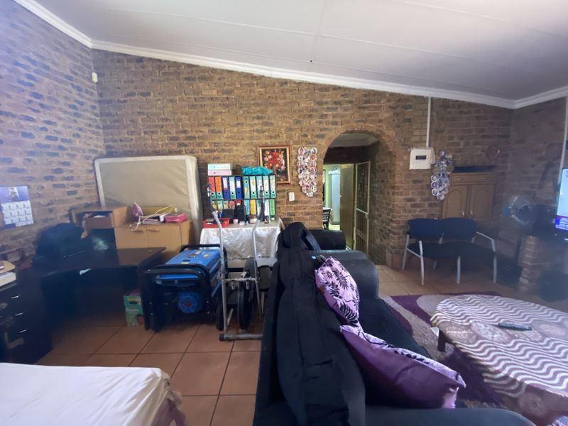 A living room featuring exposed brick walls, tiled flooring, and an arched doorway leading to an adjacent space.
