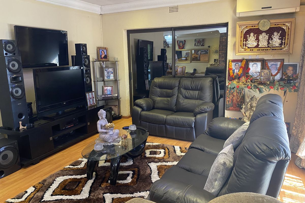 A comfortable living room featuring laminate flooring, a split-system air conditioner, and a sliding glass door leading to an adjacent space.