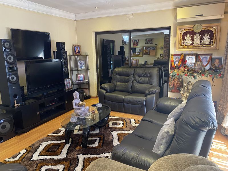 A comfortable living room featuring laminate flooring, a split-system air conditioner, and a sliding glass door leading to an adjacent space.