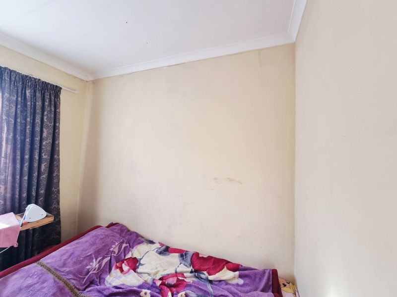 A bedroom corner featuring plain walls with visible scuff marks and a standard ceiling cornice.