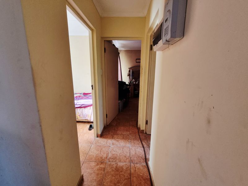 A functional hallway featuring tiled flooring and a wall-mounted prepaid electricity meter, providing access to adjacent rooms.